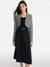 a lady in a black and white check crop jacket and black midi dress with belt